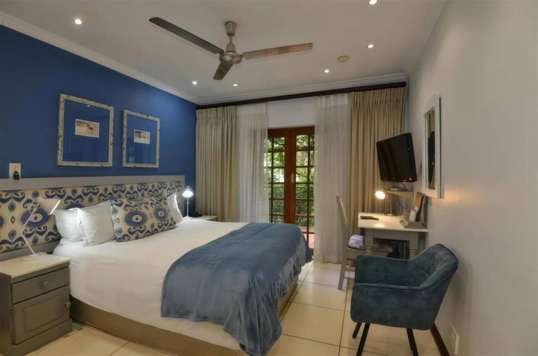 Blue-accented standard room with a king bed, desk and balcony doors