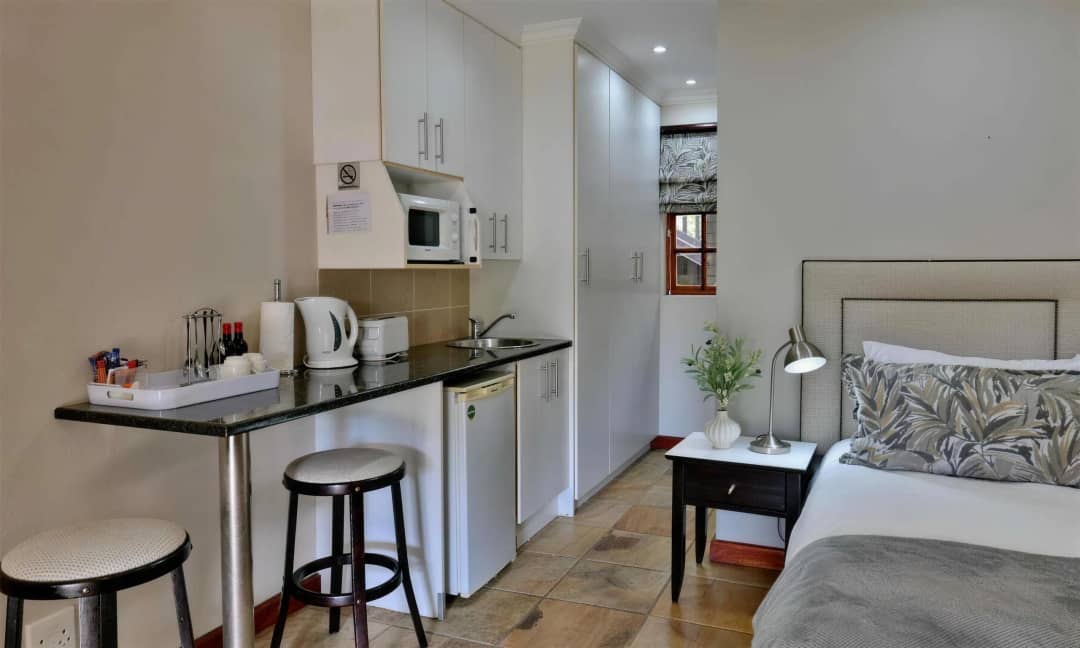 Studio room with kitchenette, bar stools, and bedside table.