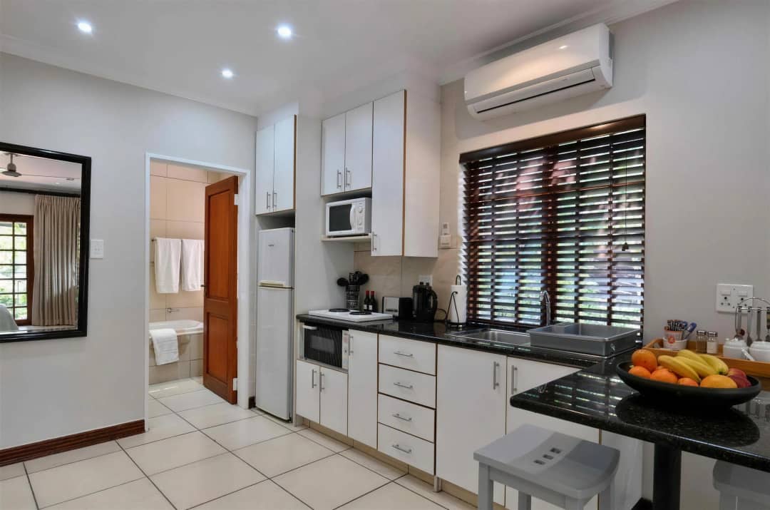 Kitchenette with fridge, microwave, fresh fruit bowl, and bathroom view.
