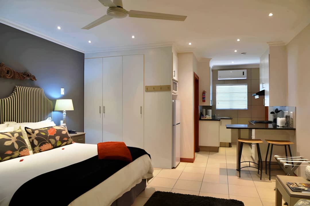 Bedroom with built-in wardrobes opening onto a compact kitchenette area.