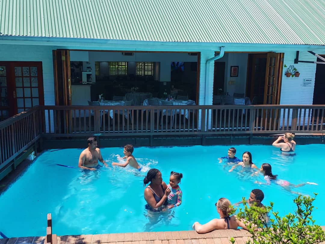 Families swimming in outdoor pool beside the covered dining terrace.