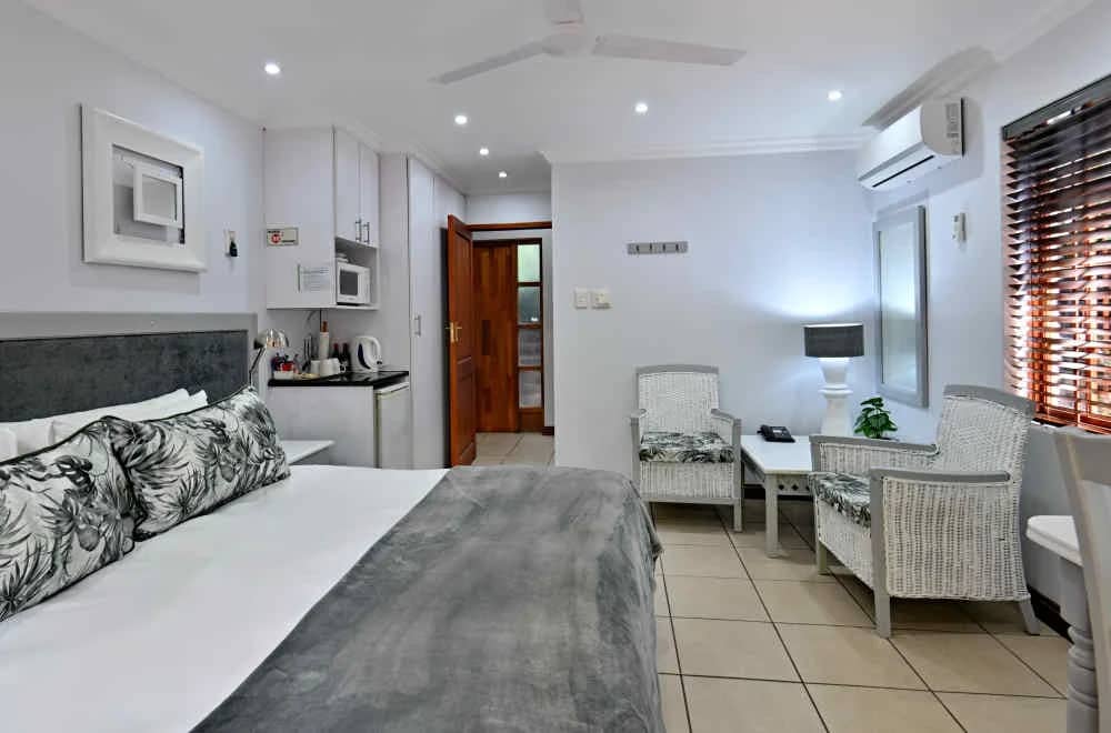 Standard room with a king bed, kitchenette corner and two wicker armchairs