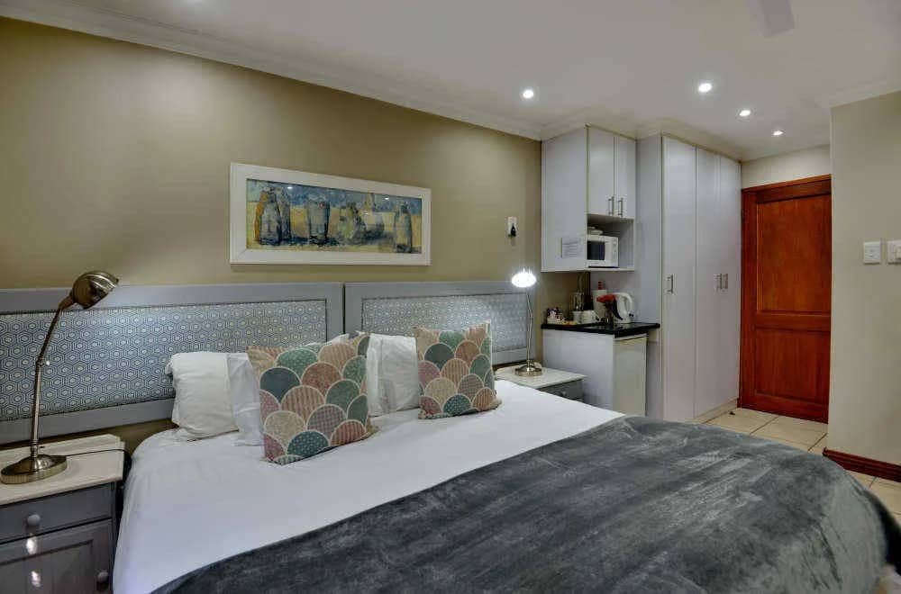 King bed with a patterned headboard and a kitchenette corner with microwave and kettle
