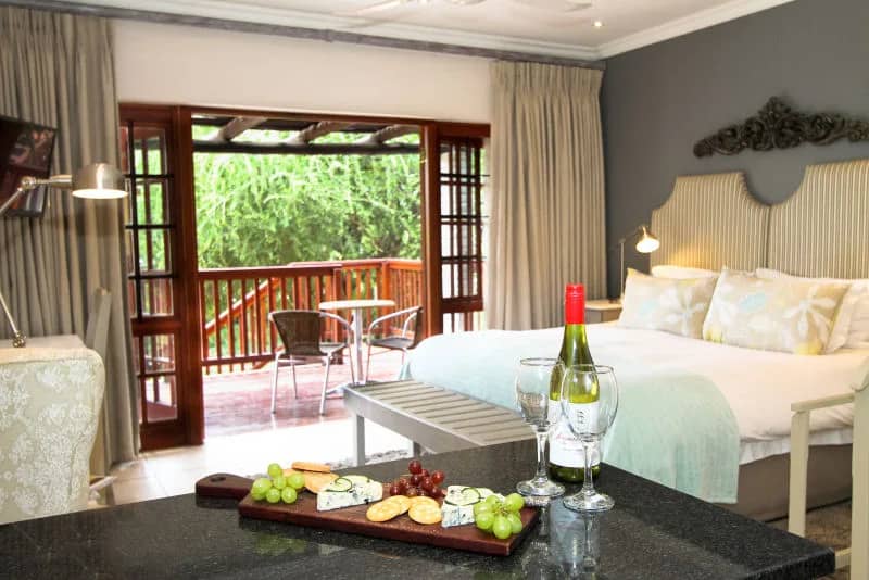 Room with a double bed and doors to a private patio, a cheese platter and wine set out
