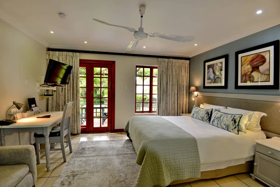 Room with a double bed, desk and French doors